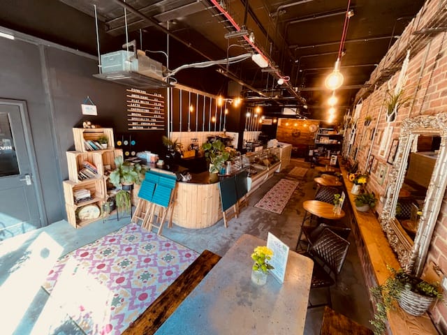 Inside Steam & Bean: brick walls, wooden tables, green plants and upholstered seating